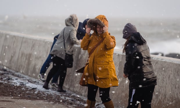 People walk through flying sea foam spray in Porthcawl. Gusts of more than 90mph and heavy rain battered the UK. Photograph: Polly Thomas/Getty Images
