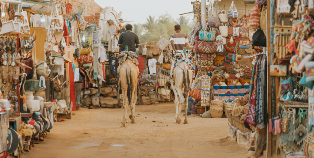 Tourists riding camels exploring nubian village market