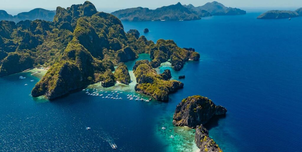 the dramatic limestone cliffs, turquoise waters, and island-hopping boats of El Nido, Palawan in the Philippines.